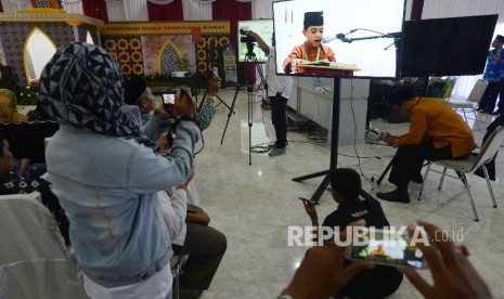 Penonton mengabadikan kafilah yang membacakan ayat suci Al Quran melalui layar saat menjalani sesi final lomba tartil Al Quran dalam rangkaian MTQ Nasional ke XXVI yang diadakan di Aula Rinjani Gedung BKD, Kota Mataram, Nusa Tenggara Barat, Jumat (5/8). 