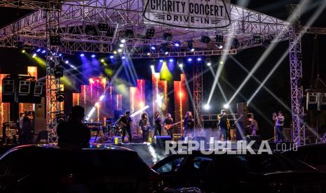 Penonton menyaksikan dari atap mobil terbuka pada konser musik.