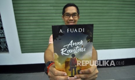 Penulis novel Ahmad Fuadi berfoto sekaligus memperlihatkan novelnya disela-sela saat wawancara di Kantor Republika, Jalan Warung Buncit, Jakarta, Selasa (5/9). 