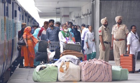 Penumpang berdiri dengan barang-barang mereka setelah turun dari Samjhauta Express, kereta yang menghubungkan Delhi di India dan Lahore di Pakistan, di Attari, sebuah kota di sepanjang perbatasan dengan Pakistan, Punjab, India utara, Kamis (8/8).