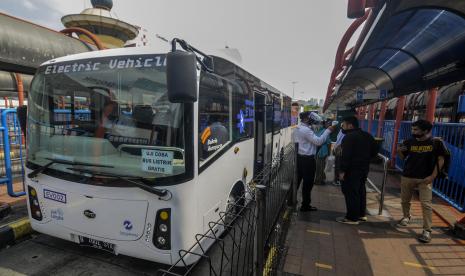 Penumpang diukur suhu tubuhnya saat akan menaiki bus listrik Transjakarta di Terminal Blok M, Jakarta.