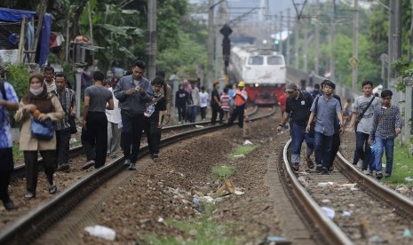 Penumpang Kereta Rel Listrik (KRL) dari Stasiun Cikini berjalan kaki menuju Stasiun Manggarai imbas anjloknya KRL rute Manggarai-Duri di antara lintasan Manggarai-Sudirman, Manggarai, Jakarta, Rabu (6/4).