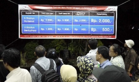 Penumpang KRL membaca pengumuman kenaikan tarif KRL Commuter Line di Stasiun Bekasi, Selasa (14/10).