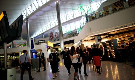 Penumpang melewati sederetan toko dan restoran di Bandara Heathrow, Inggris.