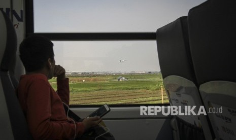 Penumpang melihat pesawat terbang dari dalam kereta bandara Railink di Tangerang, Senin (15/10). 