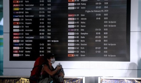 Penumpang melintas di dekat layar informasi penerbangan di Terminal Keberangkatan Internasional Bandara Internasional I Gusti Ngurah Rai, Bali, Selasa (4/2/2020). Pemerintah melalui Kementerian Perhubungan memutuskan penundaan penerbangan dari dan menuju seluruh destinasi di 