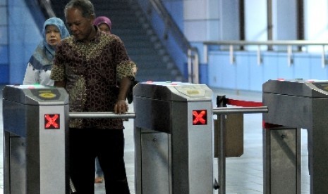 Penumpang melintasi pintu tiket elektronik Kereta Rel Listrik (KRL) saat tiba di Stasiun Juanda, Jakarta, Senin (19/8).