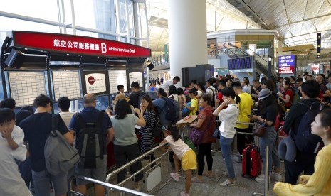 Penumpang memeriksa informasi penerbangan di meja pelayanan di Bandara Internasional Hong Kong, Hong Kong, Senin (12/8).