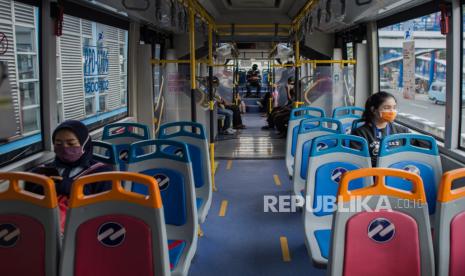 Penumpang menerapkan jarak sosial saat menaiki bus Transjakarta di Halte Harmoni, Jakarta.