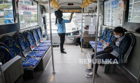 Penumpang menerapkan jarak sosial saat menaiki bus Transjakarta di Halte Harmoni, Jakarta.