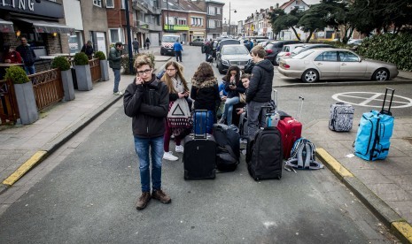 Penumpang menunggu dengan barang-barang mereka dekat bandara Brussels di Zaventem, Belgia, (22/3). Puluhan orang tewas dan terluka dalam ledakan ganda di ruang keberangkatan dari Bandara Zaventem di Brussels.