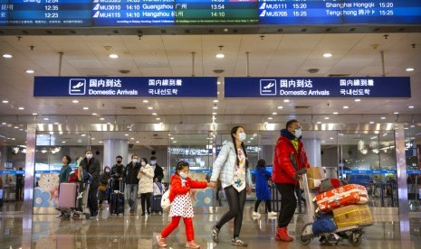 Penumpang pesawat mengenakan masker melewati papan pengumuman menunjukkan pembatalan penerbangan dari Wuhan di Bandara Beijing, Kamis (23/1). Pemerintah menutup akses ke kota Wuhan yang berpenduduk 11 juta jiwa akibat virus korona. 