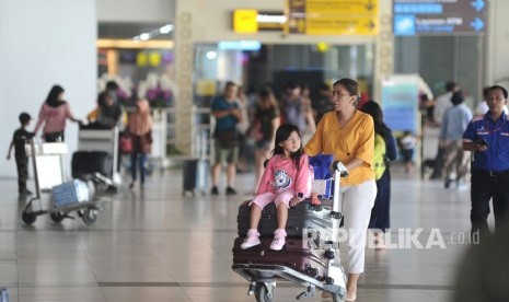 Penumpang pesawat udara membawa barang bawaan di Terminal Domestik Bandara Internasional I Gusti Ngurah Rai, Bali, Kamis (19/12/2019). 