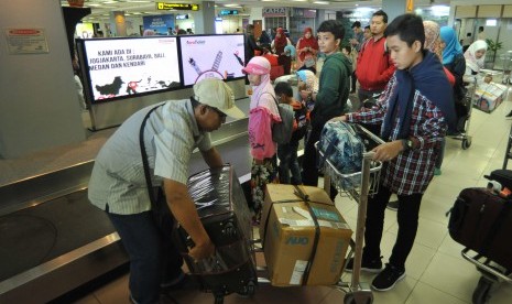 Penumpang pesawat udara mengemasi barang bagasi mereka setibanya di Bandara Internasional Minangkabau (BIM), Padangpariaman, Sumatra Barat, Kamis (7/6). 