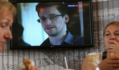 Penumpang tengah bersantap di sebuah cafe di Bandara Transit Sheremetyevo Moskow, dengan layar televisi yang menayangkan berita tentang Edward Snowden.