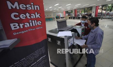 Penyandang disabilitas Rahmat Iqbal (kanan) didampingi mahasiswa jurusan teknik industri ITTS Moch Bagus Indrastata (kedua kanan) meraba cetakan huruf braille dari mesin cetak braille di Gedung Institut Teknologi Telkom Surabaya, Jawa Timur, Rabu (28/4/2021). Pengembangan mesin cetak braille dengan fitur suara (voice) tersebut merupakan bentuk kepedulian PT Telkom Indonesia terhadap penyandang disabilitas yang disalurkan melalui program CSR kepada Yayasan Tan Miyat bekerja sama dengan ITTelkom Surabaya dan Institut Teknologi Sepuluh Nopember Surabaya (ITS).