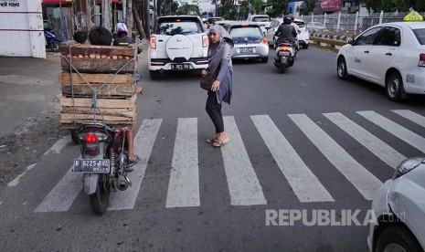 Penyeberang jalan berusaha menyeberang di zebra cross sementara pengendara kendaraan bermotor tetap melaju (Ilustrasi)