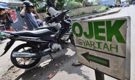  Penyedia jasa  angkutan sepeda motor (ojek) melayani penumpang di pangkalan Ojek Syariah, Jalan KH Abdullah Syafi'ie, Tebet Barat, Jakarta, Selasa (7/1).   (Republika/Aditya Pradana Putra)