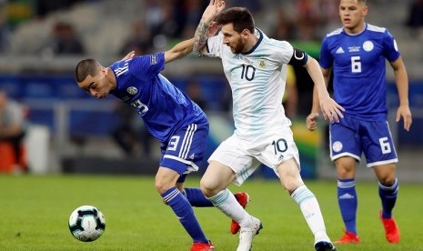 Penyerang Argentina Lionel Messi (tengah) berebut bola dengan pemain Paraguay Miguel Almiron pada laga Grup B Copa America 2019.