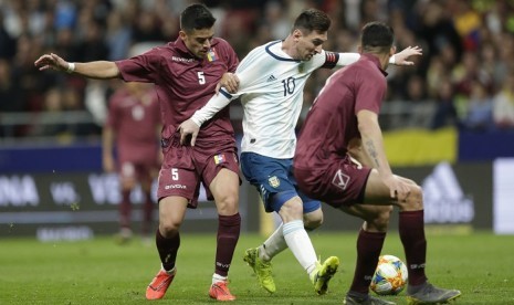 Penyerang Argentina Lionel Messi (tengah) diapit dua pemain Venezuela.