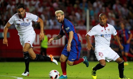 Penyerang Barcelona Lionel Messi (tengah) dijaga pemain Sevilla.