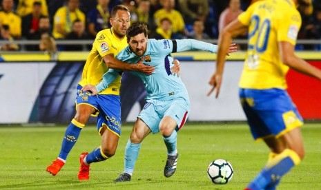 Penyerang Barcelona Lionel Messi (tengah) ditahan pemain Las Palmas Dani Castellano dalam laga pekan ke-26 La Liga di Stadion Gran Canaria, Pulau Canary, Las Palmas, Jumat (2/3). Barcelona ditahan imbang 1-1.