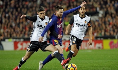 Penyerang Barcelona, Lionel Messi (tengah) saat melewati pemain Valencia.