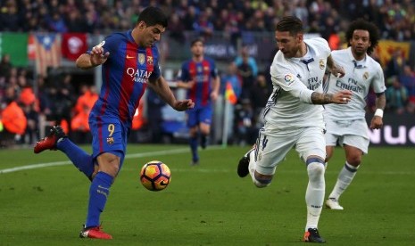 Penyerang Barcelona Luis Suarez kiri dibayangi oleh bek Real Madrid Sergio Ramos. Keduanya mencetak gol dalam pertandingan yang berakhir imbang 1-1.