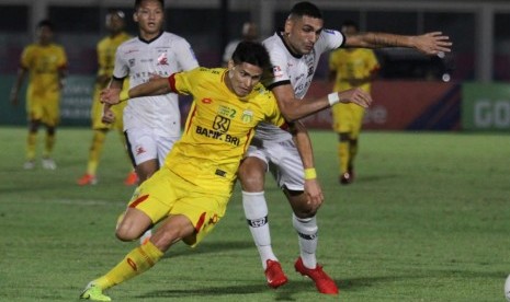 Penyerang Bhayangkara FC Ramiro Fergonzi (kuning) berebut bola dengan bek Madura United Jaimerson Silva.