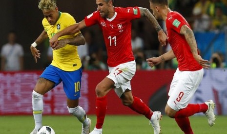 Penyerang Brasil Neymar (kiri) berebut bola dengan pemain Swiss, Valon Behrami dalam pertandingan di Grup E antara Brasil melawan Swiss, di Rostov Arena, Rusia, Ahad (17/6)