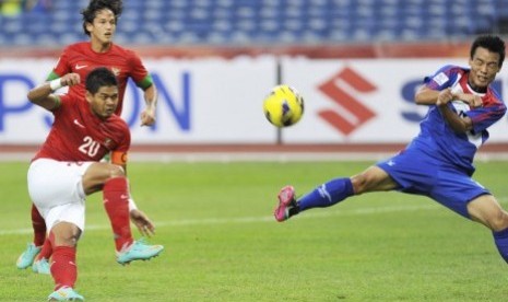 Penyerang Indonesia, Bambang Pamungkas (kiri), menendang bola dibayangi bek Laos, Ketsada Souksavanh (kanan), pada pertandingan penyisihan Grup B Piala AFF 2012 di Stadion Bukit Jalil, Kuala Lumpur, Malaysia, Ahad (25/11) petang. Pertandingan tersebut bera