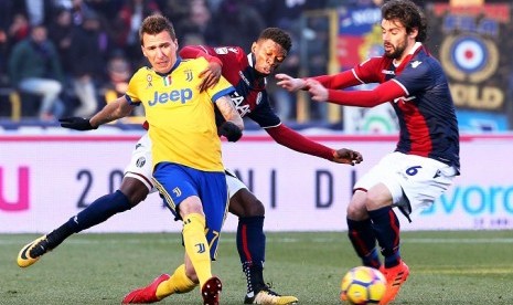 Penyerang Juventus, Mario Mandzukic (kiri) saat menghadapi Bologna dalam laga lanjutan Serie A, Ahad (17/12).