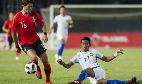 Penyerang Korea Selatan Hwang Ui-jo (kiri) berebut bola dengan pemain Malaysia Zakaria Muhammad Irfan pada laga Grup E sepak bola putra Asian Games 2018 di Stadion Jalak Harupat, Kabupaten Bandung, Jawa Barat, Jumat (17/8).