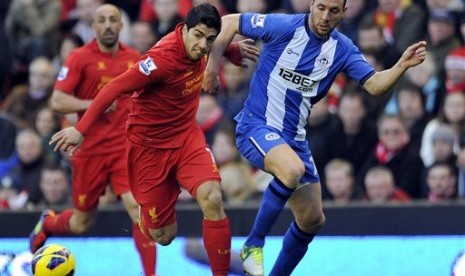 Penyerang Liverpool, Luis Suarez, saat berduel dengan bek Wigan, Ivan Ramis, di Anfield Stadium, Sabtu (17/11). Laga itu berkesudahan 3-0 untuk The Reds.