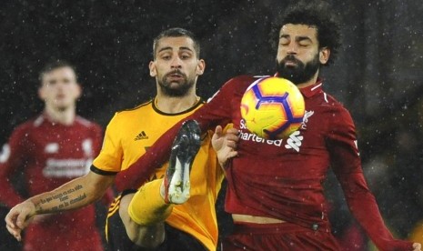 Penyerang Liverpool Mohamed Salah berusaha melindungi bola dari rebutan pemain Wolverhampton Wanderers.