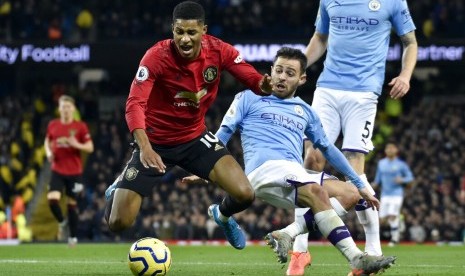 Penyerang Manchester United (MU) Marcus Rashford (kiri) dijatuhkan Bernardo Silva di kotak penalti Manchester City. Rashford mencetak gol untuk MU dari titik penalti.