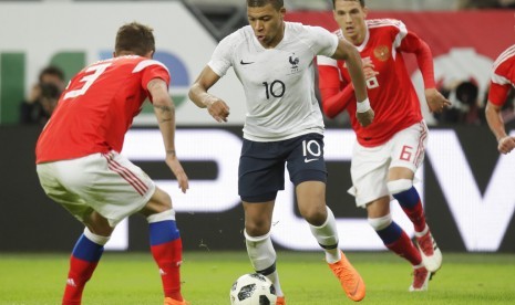 Penyerang Prancis Kylian Mbappe berusaha melewati penjagaan pemain Rusia.