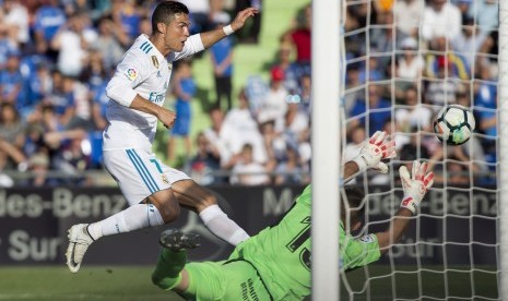 Cristiano Ronaldo (kiri) menaklukan kiper Getafe Vicente Guaita pada laga La Liga Spanyol pada lanjutan La Liga Spanyol di Stadion Coliseum Alfonso Perez, Sabtu (14/10) waktu setempat.