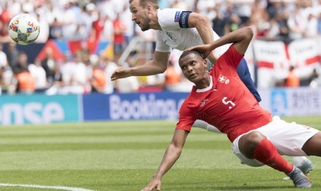 Penyerang timnas Inggris Harry Kane (baju putih) dihalangi bek Swiss Manuel Akanji pada laga perebutan peringkat ketiga UEFA Nations League, Ahad (9/6).