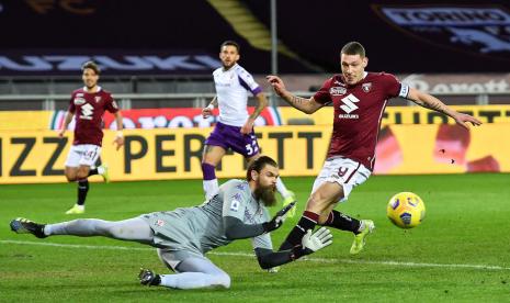 Penyerang Torino Andrea Belotti (kanan) dan kiper Fiorentina Bartolomiej Dragowski berusaha menyambut bola dalam pertandingan Serie A, Sabtu (30/1) dini hari WIB..