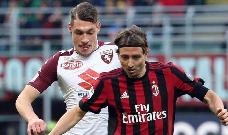 Penyerang Torino Andrea Belotti (kiri) dan Gelandang AC MIlan Riccardo Montolivo (kanan) dalam pertandingan kedua klub di Stadion San Siro, Milan, Italia, Ahad (26/11). 