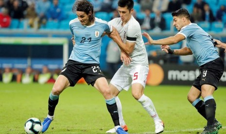 Penyerang Uruguay Edinson Cavani (kiri) dijaga pemain Jepang pada laga Copa America 2019.