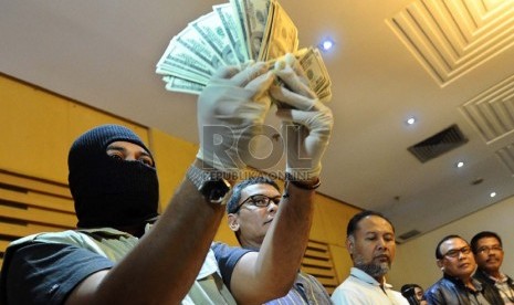  Penyidik KPK menunjukan uang dolar saat gelar barang bukti dalam operasi tangkap tangan di kantor KPK, Jakarta, Ahad (15/12).