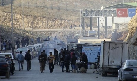 People carrying their belongings walk at the Syrian border crossing of Bab al-Hawa, at the Syrian-Turkish, Idlib Governorate December 20, 2013. 