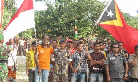 People from Indonesia and Timor Leste hoist flags of both countries after the closing ceremony of military's personnel community service in Mutis distric (Indonesia) and Oecusse district (Timor Leste). Timor Leste plans to open border trade zone in Oecusse