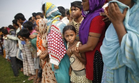 People gather in front of mass graves during the burial of unidentified garment workers, who died in the collapse of the Rana Plaza building in Savar, in Dhaka May 1, 2013. 