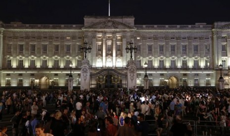 People gather outside a floodlit Buckingham Palace in London to mark the birth of a baby boy to Prince William and Kate, Duchess of Cambridge, Monday, July 22, 2013. 