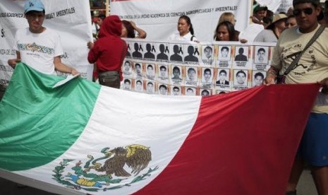 People hold a Mexican flag during a demonstration to demand information for the 43 missing students of the Ayotzinapa teachers' training college, in Iguala, the southern Mexican state of Guerrero, October 22, 2014.