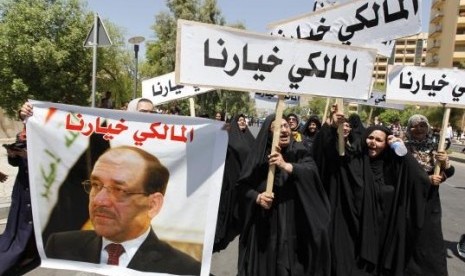 People hold a portrait of Nuri al-Maliki and signs as they gather in support of him in Baghdad August 13, 2014.