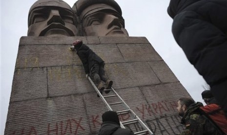 People paint on the KGB officers monument in Kiev, Ukraine, Sunday, Feb. 23, 2014. 